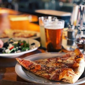 a plate of food with a slice of pizza on a table
