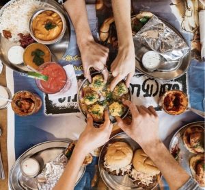 a group of people sitting at a table with plates of food
