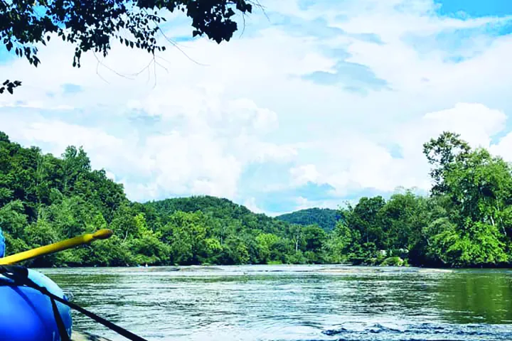 a boat floating along a river next to a body of water